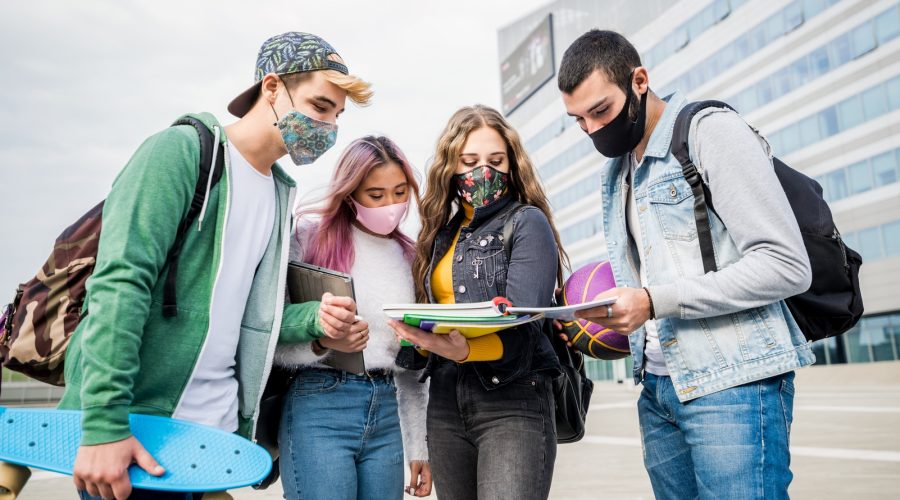 Multiracial students with face mask studying at college campus - New normal lifestyle concept with young students having fun together outdoor.